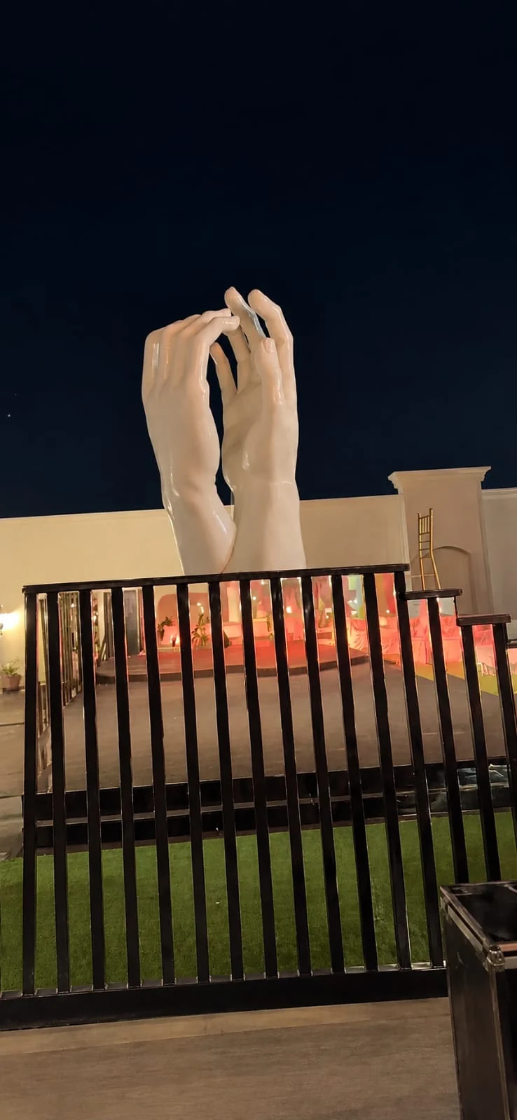 مجسم يدين ضخمتين مثبت بموقع خارجي ليلا كعنصر ديكور فني
