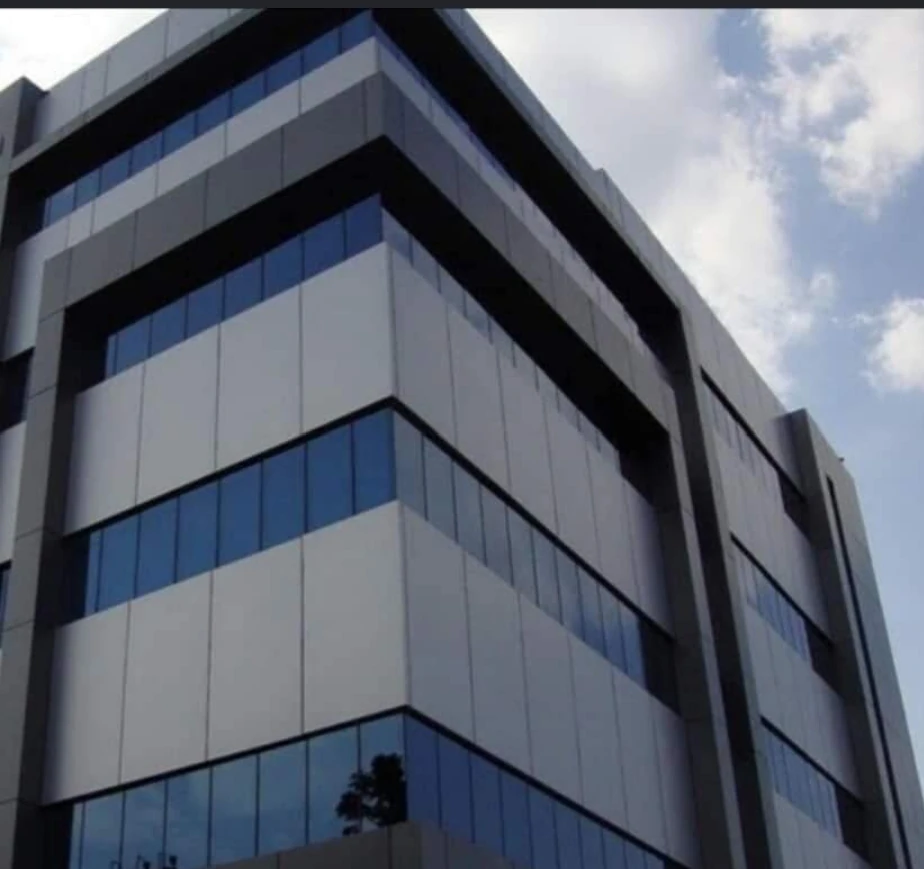 واجهة متعددة الأدوار بألواح معدنية وزجاج أزرق وتفاصيل هندسية